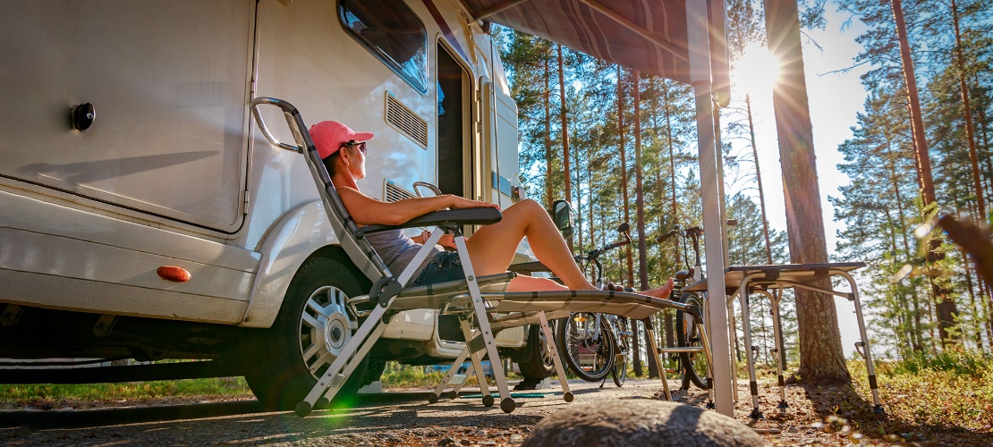 Tourist entspannt sich neben seinem Wohnwagen
