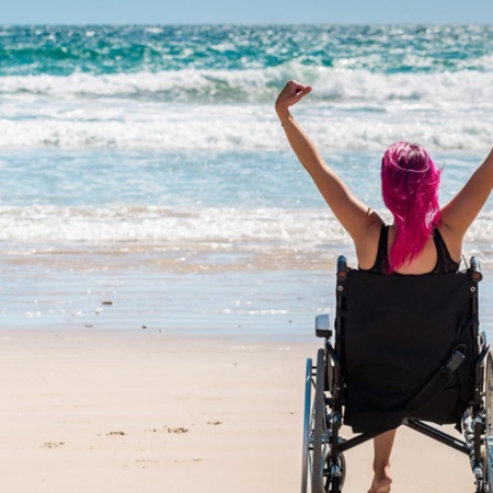 Turista de cadeira de rodas desfrutando da praia