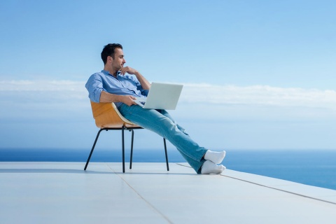  海を眺めながらノートパソコンで働く男性