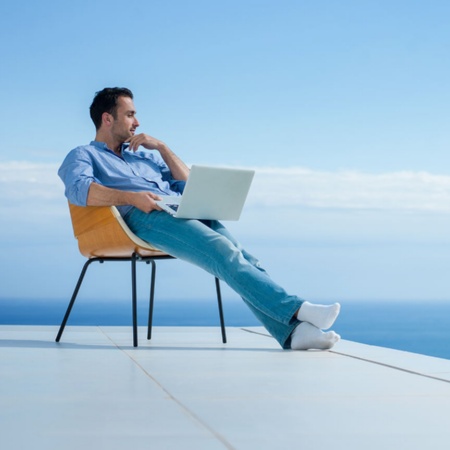 Hombre trabajando con un portátil con vistas al mar
