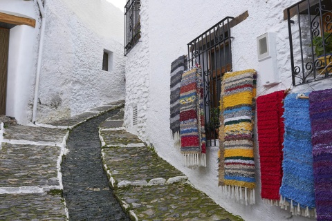 Una calle típica de Pampaneira (Granada), adornada con las mantas tradicionales de La Alpujarra