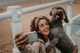 Touriste prenant un selfie avec son animal de compagnie sur une plage de Gijón, Asturies