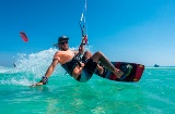 Young man kitesurfing over clear waters