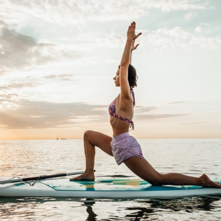 Femme faisant du yoga sur une planche Sup