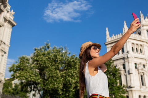 Турист делает селфи на площади Сибелес в Мадриде