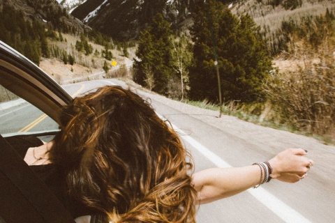  Girl leans out of a car window on a mountain road