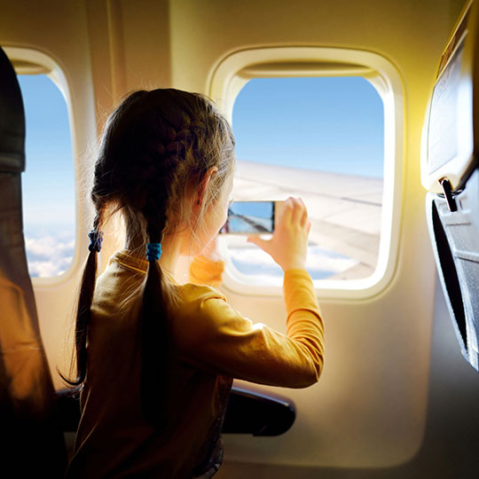 Bambina che scatta una foto dal finestrino dell'aereo