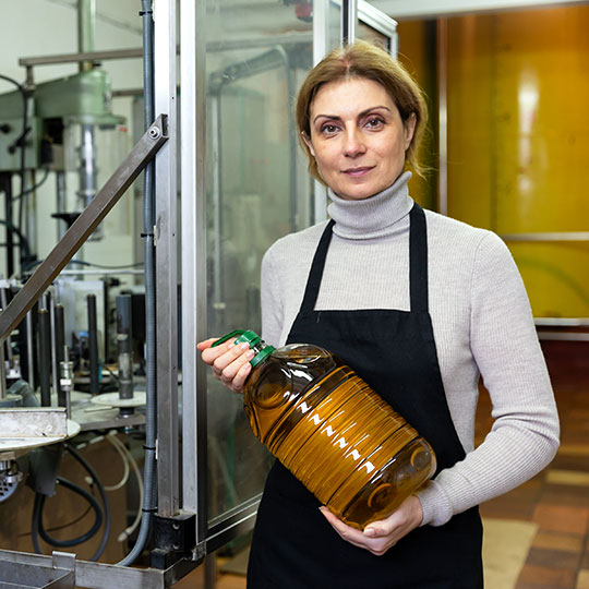Mujer en una fábrica de aceite muestra una garrafa