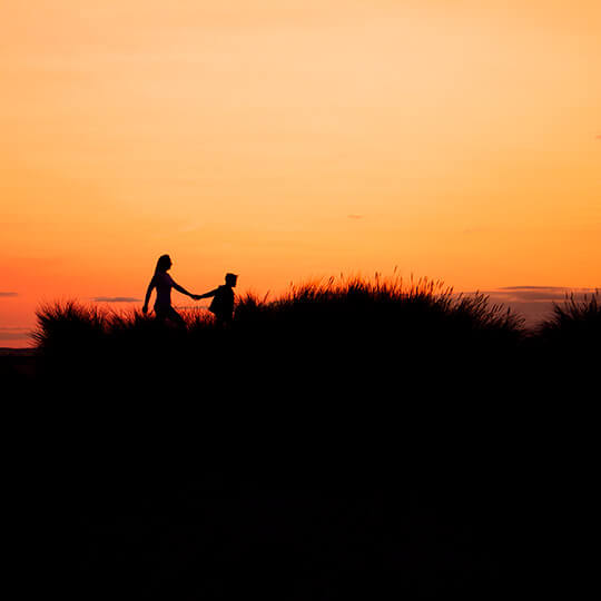 Mãe e filho caminhando por uma duna