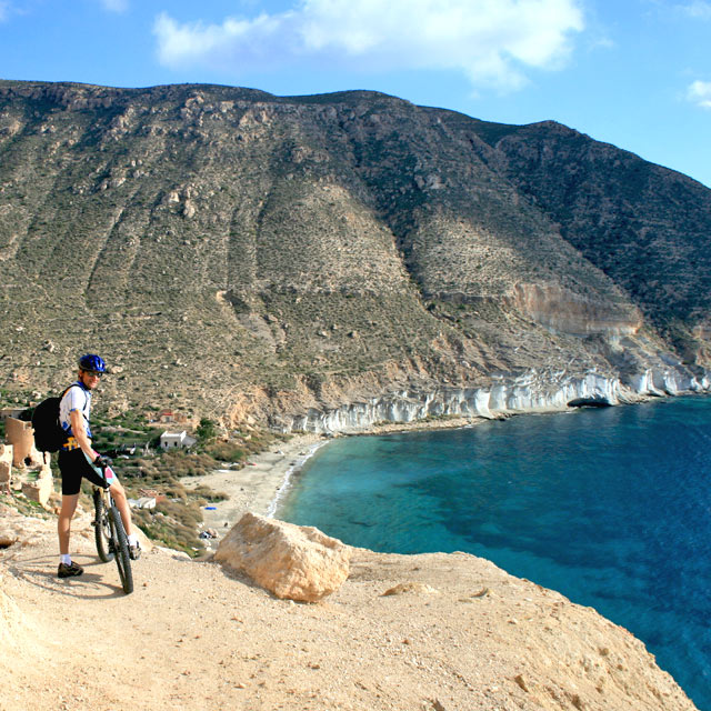 Ciclista mentre contempla una cala a Cabo de Gata, Almería