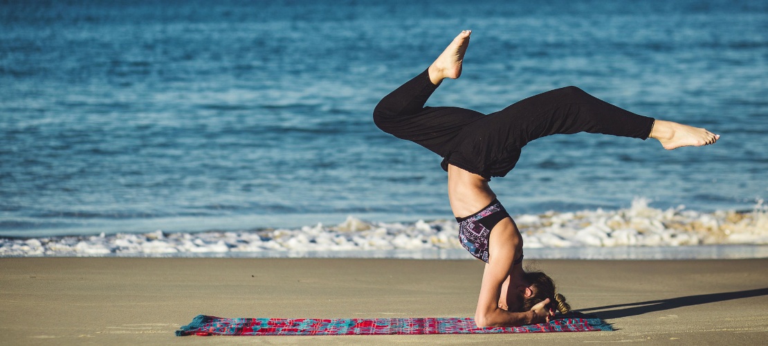 Jeune fille en train de pratiquer le yoga sur la plage