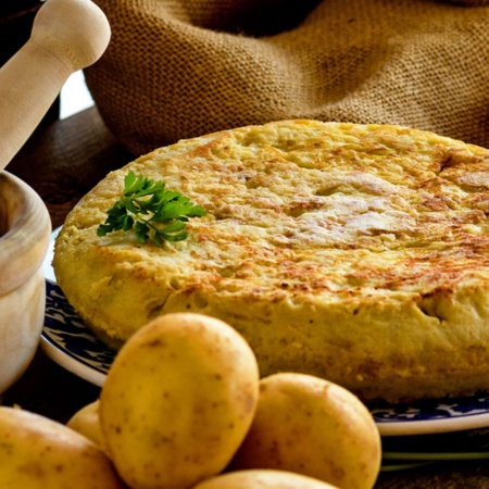 Tortilla de patata con productos para hacerla y mortero