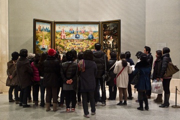 Группа посетителей в зале Босха разглядывает картину «Сад земных наслаждений»