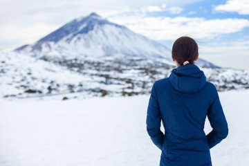 Junge Frau betrachtet den schneebedeckten Teide-Vulkan