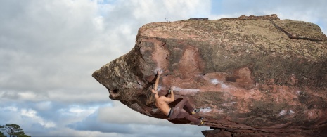 Mężczyzna wspinający się na blok skalny w Sierra de Albarracín w prowincji Teruel, Aragonia